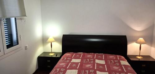 a bedroom with a bed with a red blanket and two lamps at A Casa de Santana in Santana