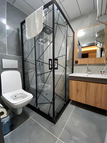 a bathroom with a toilet and a glass shower at Otel OrtaDoğu in Urfa