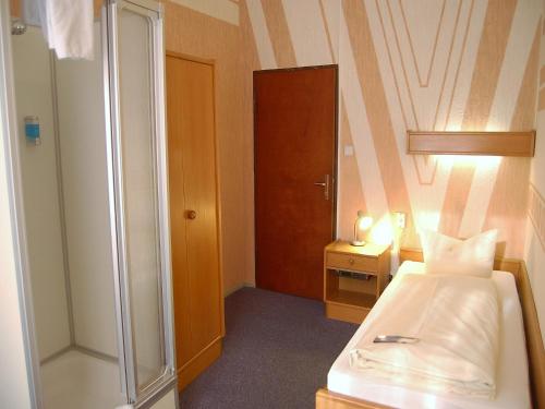ein kleines Schlafzimmer mit einem Bett und einer Dusche in der Unterkunft Hotel Graf Pückler in Berlin