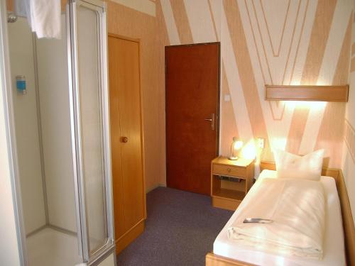 - une petite chambre avec un lit et une douche dans l'établissement Hotel Graf Pückler, à Berlin