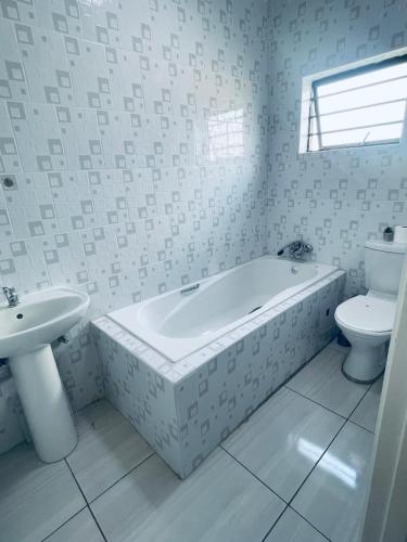 a bathroom with a tub and a toilet and a sink at Parklane Bed and breakfast in Gaborone