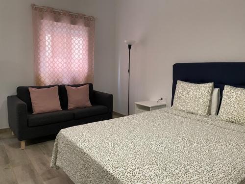 a bedroom with a bed and a couch at Jandia Arena Habitación con baño - aire acondicionado in Morro del Jable
