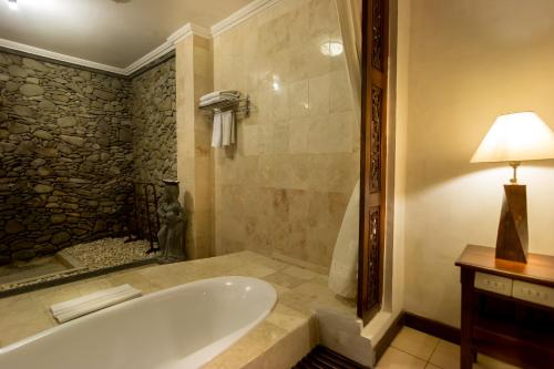 a bathroom with a bath tub and a lamp at Sahadewa Resort & Spa in Ubud