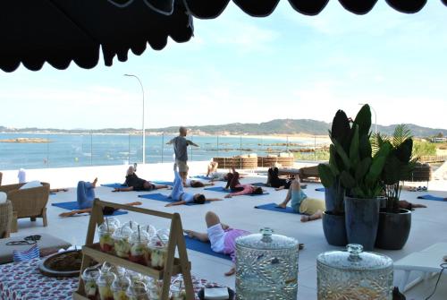 Eine Gruppe von Menschen, die am Strand Yoga machen in der Unterkunft Hotel Delfin Azul in A Lanzada