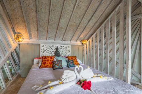 a bedroom with a bed with swans on it at BoHo Bingin Beach Bali in Uluwatu