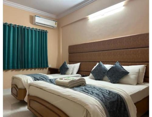 two beds in a hotel room with green curtains at Hotel shree darshan Dwarka in Dwarka