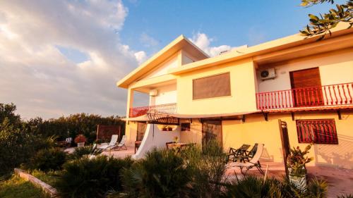 a yellow house with a balcony and chairs at Case Bongiovi in Sciacca