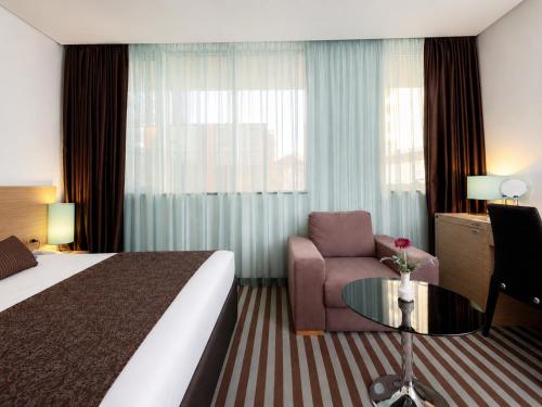 a hotel room with a bed and a chair and a table at Hotel Nartel in Prishtinë