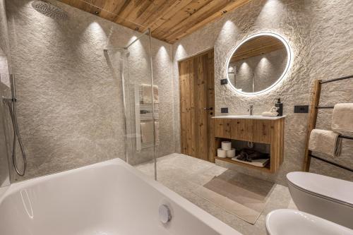 a bathroom with a tub and a sink and a mirror at Dosplain Panoramic Apartments in Santa Cristina Gherdëina