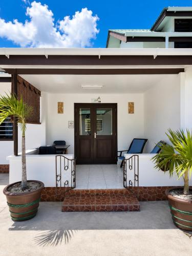 a front door of a house with two palm trees at Roche Kerlan Apartments in Anse Kerlan