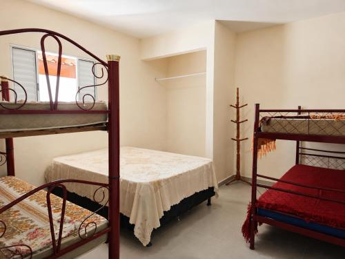 a bedroom with two bunk beds and a red chair at Acolhedora casa renovada - Piscina e a 100m da praia in Caraguatatuba
