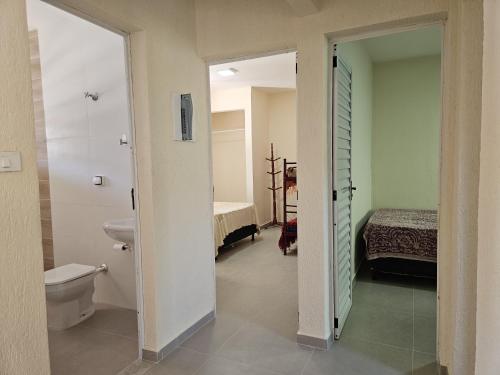 a bathroom with a toilet a sink and a bed at Acolhedora casa renovada - Piscina e a 100m da praia in Caraguatatuba