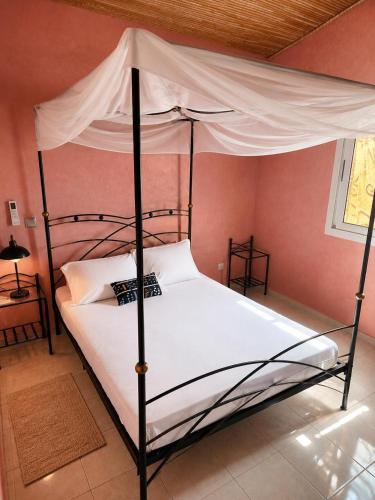 a bedroom with a canopy bed with white sheets at Résidence Les Bernier in Nianing