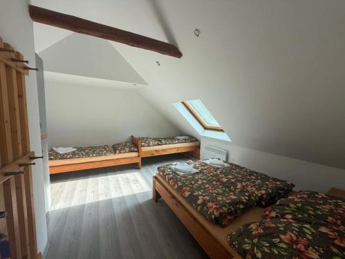 a attic room with two beds and a window at Statek u Potoka in Vimperk