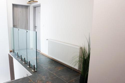 a hallway with a glass staircase and a potted plant at Termál Vendégház in Leányfalu