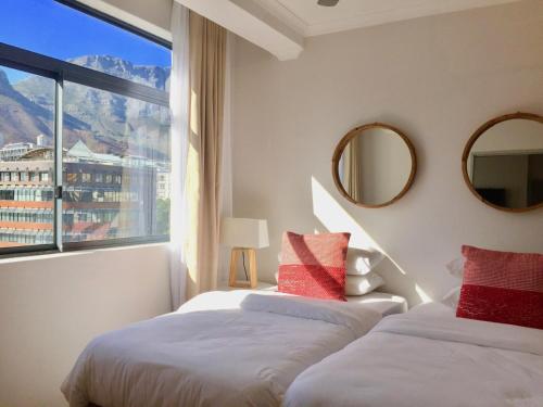 Dos camas en una habitación con una gran ventana. en Urban Oasis at The Square, en Ciudad del Cabo