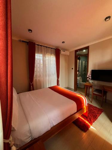 a bedroom with a bed and a living room with a piano at Armatyr Motel in Kampala