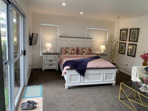 a bedroom with a bed and two tables and a window at Wattle Downs Palm Beach Studio in Auckland