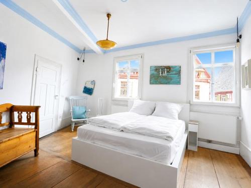 a white bedroom with a bed and a chair at Stilhaus 1730 in Königsbach Stein