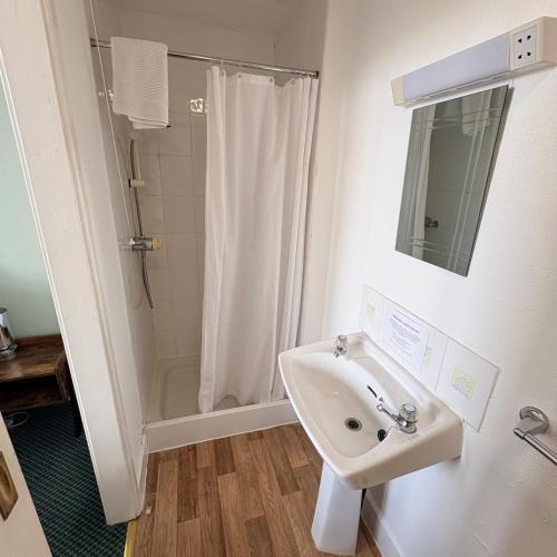 a white bathroom with a sink and a shower at The Sandpiper in Barmouth