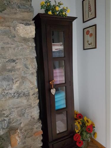 a wooden cabinet with a glass door next to a stone wall at B&B La Cà De La Frà in Gravedona