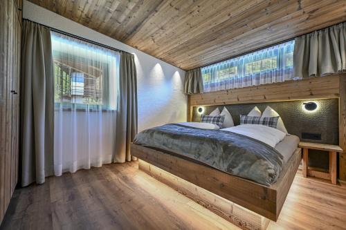a bedroom with a large bed and two windows at Dosplain Panoramic Apartments in Santa Cristina Gherdëina
