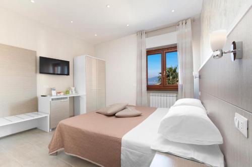 a white bedroom with a bed and a window at Rooms Sorrento in Sorrento