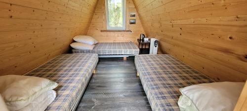 a room with two beds in a wooden cabin at Vigio Brasta camping in Elektrėnai