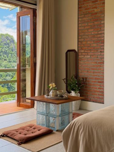 a bedroom with a bed with a table and a window at หมี่ก่าโฮมสเตย์ in Ban Pha Mi