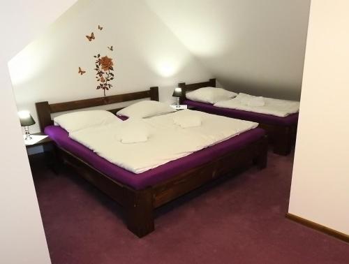2 camas en una habitación con sábanas moradas y blancas en Dovolenkový Dom Tatry, en Vysoke Tatry - Tatranske Matliare