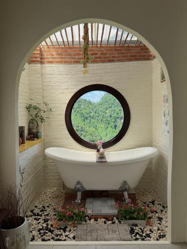 a bath tub in a bathroom with a window at หมี่ก่าโฮมสเตย์ in Ban Pha Mi