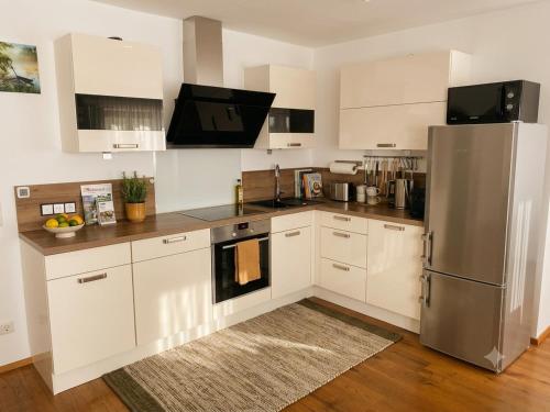 a kitchen with white cabinets and a stainless steel refrigerator at Wohnen im Grünen - Landidylle mit Komfort Nähe Linz in Pregarten