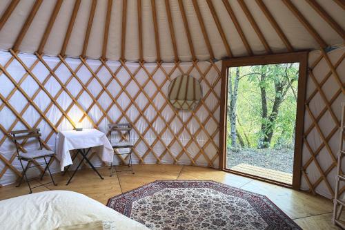 a room with a bed and a table in a yurt at Yourte pour deux - Voie Bleue in Bayon