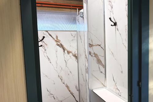 a glass shower door with a white marble wall at Yourte pour deux - Voie Bleue in Bayon