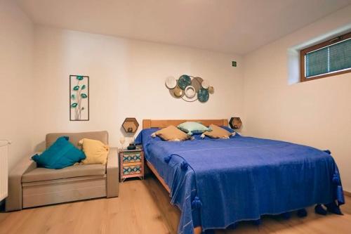 a bedroom with a blue bed and a couch at Három Sziget Vendégház in Dunasziget