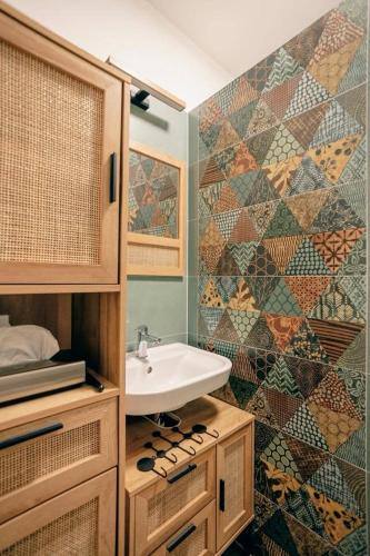 a bathroom with a sink and a mosaic wall at Három Sziget Vendégház in Dunasziget