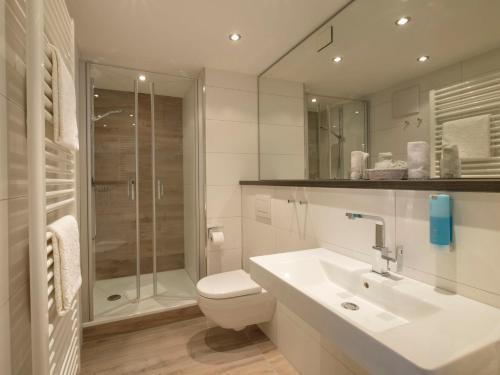 a bathroom with a toilet and a sink and a shower at Hotel Rosenstock - Erwachsenenhotel - Adults only 15 plus in Fischen