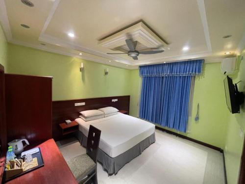 a bedroom with a white bed and a blue curtain at Vista Villa in Hithadhoo