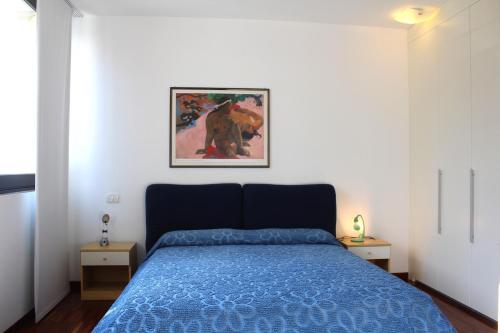 a bedroom with a blue bed and a picture on the wall at Residenza Nervesa in Lignano Sabbiadoro