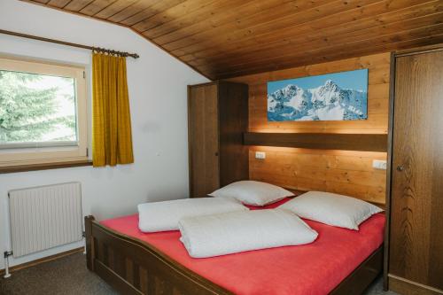 a bedroom with a red bed with two white pillows at Almblick Appartements in Sankt Jakob in Defereggen