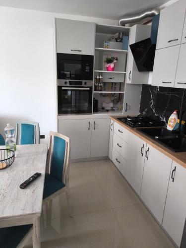 a kitchen with white cabinets and a table with chairs at Apartament cu 2 camere situat la etajul al doilea in Rădăuţi