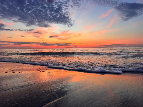 a sunset on a beach with the ocean at Domki Cała Naprzód in Jastrzębia Góra
