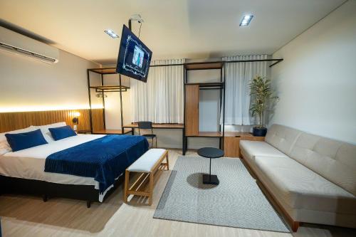 a bedroom with a bed and a couch and a tv at ELLEVA STUDIOS | Studio moderno com coworking e rooftop em Sinop in Sinop