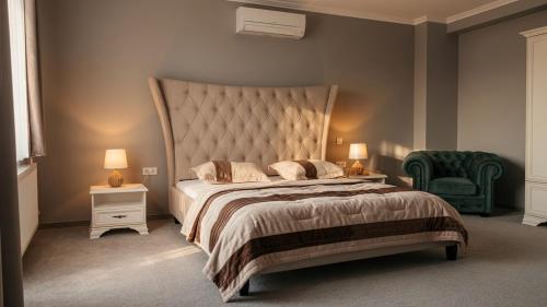 a bedroom with a large bed and a green chair at Pearl Home in Békéscsaba