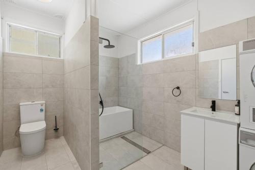 a white bathroom with a toilet and a sink at Central Coast Waterfront 2BR with Jetty Access in Koolewong