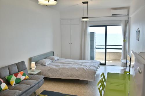 a bedroom with a bed and a couch and a window at Stadem Studios in Larnaca