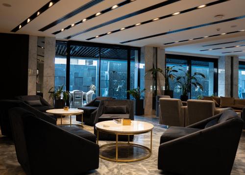 a waiting room with couches and tables and windows at The V Hotel in Baghdād