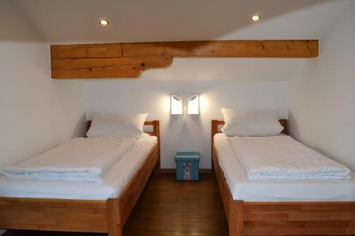 two twin beds in a room with wooden floors at Ferienwohnung Auszeit | Chiemgau Karte in Grassau