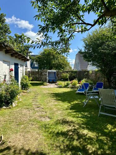 a yard with two blue chairs and a fence at Dünennest Sylt - Privatgarten mit Leuchtturmblick im Herzen von Hörnum in Hörnum