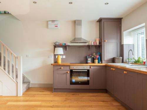 a kitchen with grey cabinets and a sink at Y Cwtsh in Llandeilo